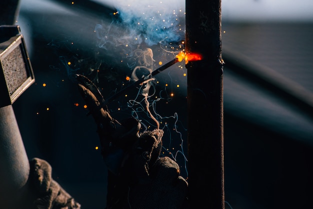 Photo d'un homme travaillant avec un soudeur en acier à l'aide d'une machine de soudage électrique en plein air