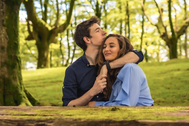 Photo horizontale frontale d'une scène tendre d'amoureux s'embrassant dans une forêt
