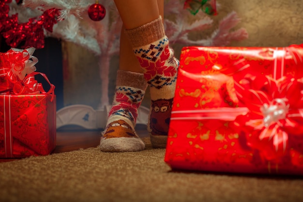 Photo horizontale de jambes féminines dans des chaussettes amusantes avec beaucoup de cadeaux de Noël. Ambiance de Noël. Nouvelle année.