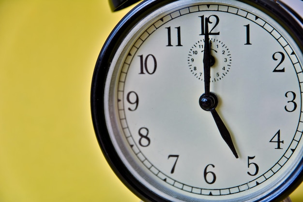 Photo d'une horloge analogique rétro vintage sur fond jaune montrant 10 heures