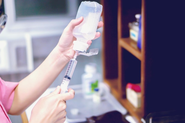 Une photo d'une infirmière remet en préparation un vaccin par injection pour le patient dans un ton clair bleu.