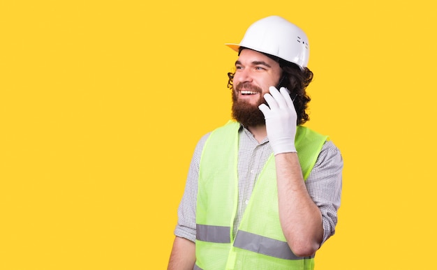 Une photo d'un jeune architecte joyeux parlant sur son téléphone est à la recherche d'un mur jaune