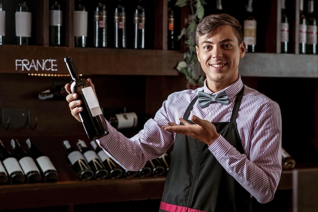 Photo D'un Jeune Barman Souriant Posant Avec Une Bouteille Ouverte