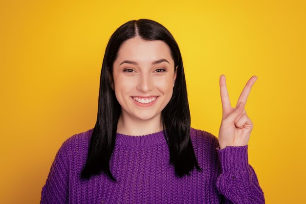 Photo de jeune belle fille heureux sourire positif show v-sign Peace cool isolé sur fond de couleur jaune