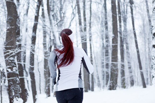 Photo d'une jeune brune fait du sport dans un parc d'hiver