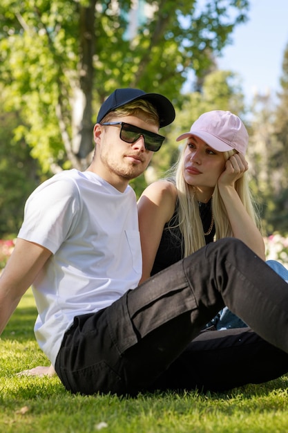 Photo de jeune couple assis sur l'herbe et regardant la caméra