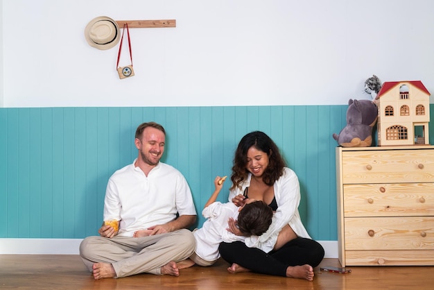 Photo d'un jeune couple joyeux et souriant, femme enceinte et son mari avec leur fils se relaxant à la maison