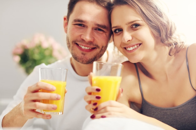 Photo de jeune couple mangeant le petit déjeuner au lit