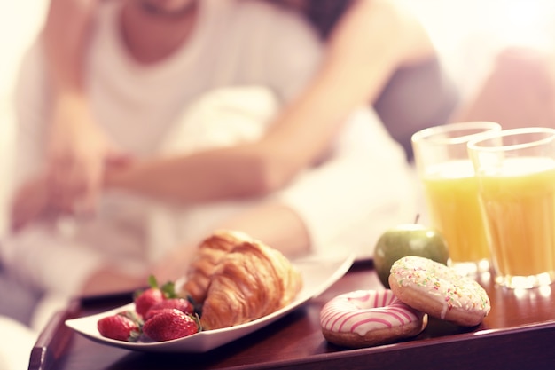 Photo de jeune couple mangeant le petit déjeuner au lit