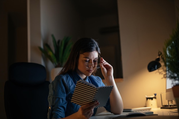 Photo d'une jeune femme d'affaires mettant des lunettes et travaillant à domicile.