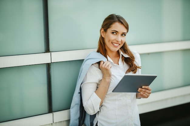 Photo d'une jeune femme d'affaires utilisant une tablette numérique à l'extérieur d'un immeuble de bureaux pendant la pause.