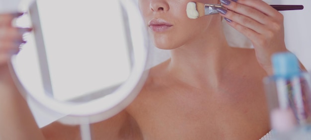 Une photo d'une jeune femme appliquant de la poudre pour le visage dans la salle de bain