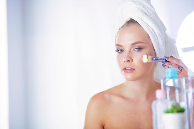 Photo une photo d'une jeune femme appliquant de la poudre pour le visage dans la salle de bain