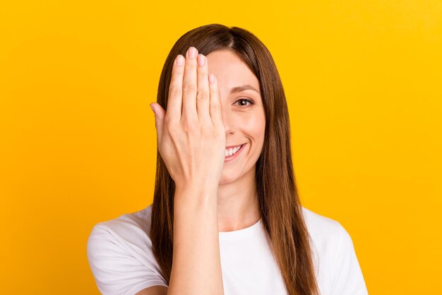 Photo photo d'une jeune femme attrayante portant un œil caché, une main sans vision, un sourire denté isolé sur un fond jaune.