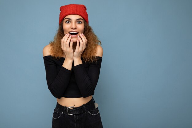 Photo d'une jeune femme brune aux cheveux ondulés, choquée et étonnée, avec des émotions sincères