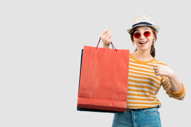 Photo de jeune femme brune à lunettes de soleil pointant sur les sacs à provisions. photo de haute qualité