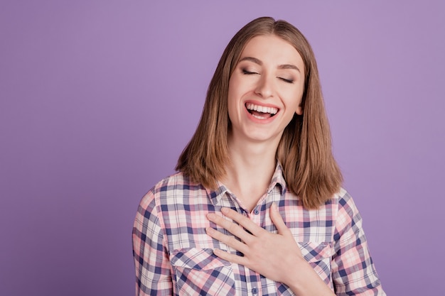 Photo de jeune femme charmante la main sur la poitrine happyp sourire positif rire isolé sur fond violet
