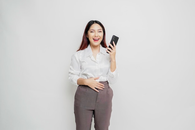 Photo d'une jeune femme excitée et affamée tenant son téléphone et se demandant quoi commander de la nourriture délicieuse isolée sur fond de couleur blanche