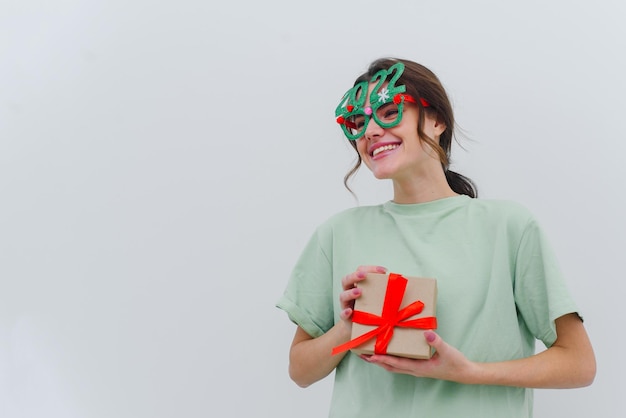 Photo d'une jeune femme excitée portant des lunettes de sapin de Noël 2022, isolée sur fond blanc. Espace de copie.