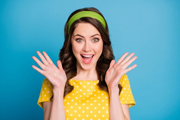 Photo d'une jeune femme folle et étonnée crier fort lever les mains porter des vêtements à pois isolés sur fond de couleur bleu