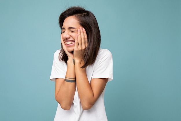 Photo de jeune femme heureuse souriante positive positive avec des émotions sincères portant des vêtements élégants isolés sur le mur avec espace de copie.