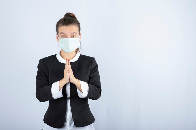 Photo de jeune femme en masque priant sur fond blanc. Photo de haute qualité