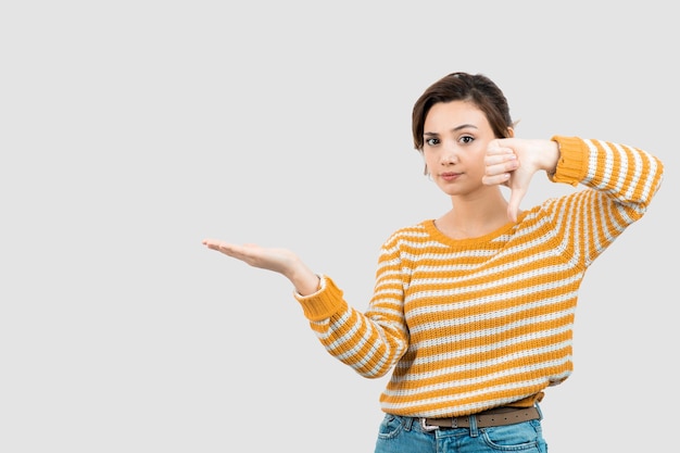 Photo d'une jeune femme montrant la paume ouverte et le pouce vers le bas