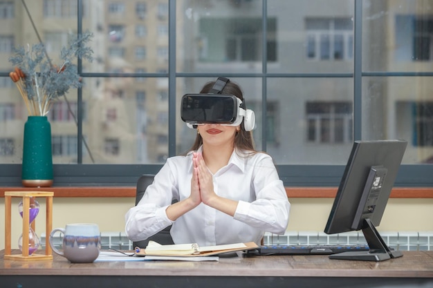 Photo d'une jeune femme portant un appareil VR et joignant ses mains