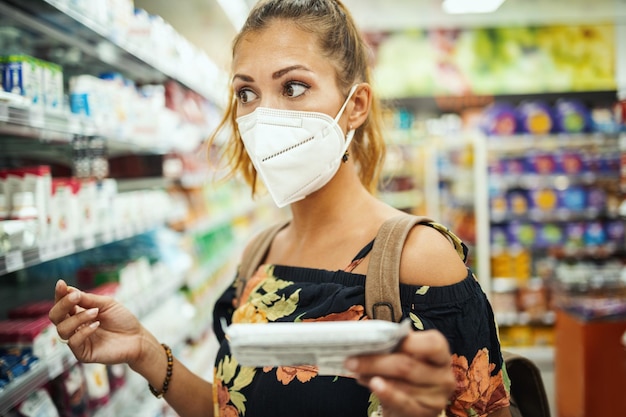 Photo d'une jeune femme portant un masque de protection N95 lors de l'achat au supermarché pendant la pandémie de Covid-19.