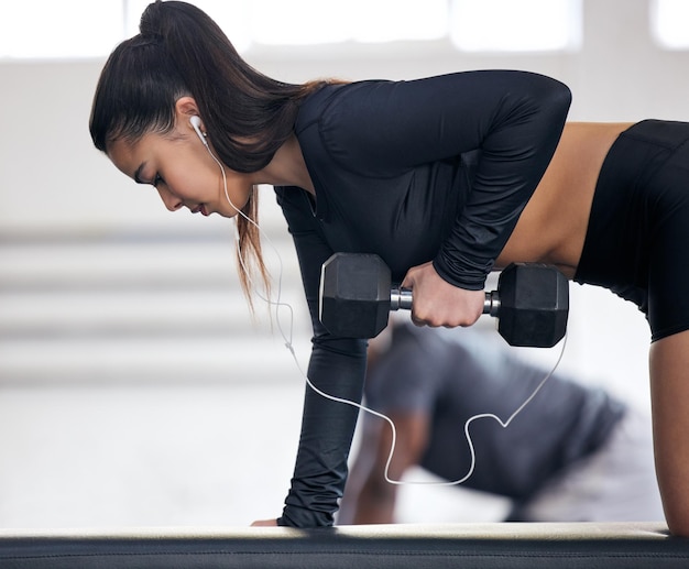 Photo d'une jeune femme qui s'entraîne avec des poids dans une salle de sport