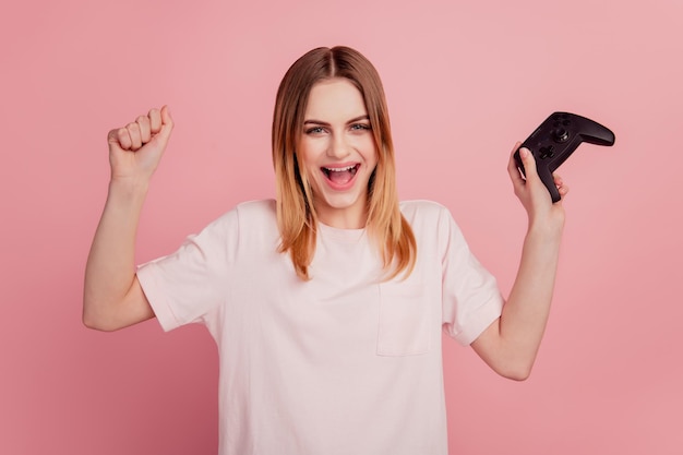 Photo de jeune femme se réjouir du succès du jeu vidéo console de victoire temps libre isolé sur fond de couleur rose