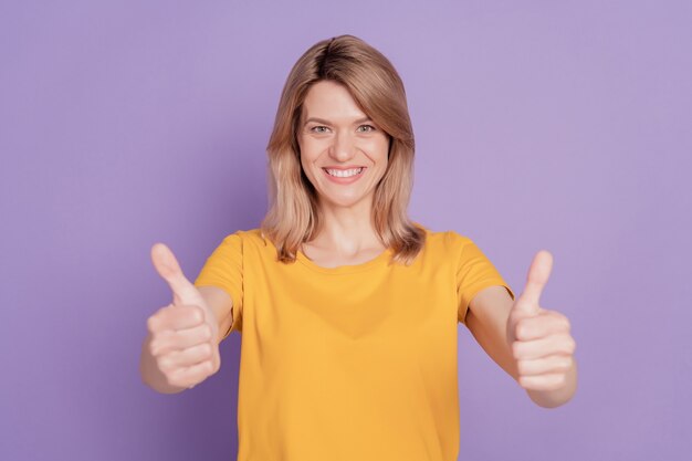 Photo de jeune femme séduisante sourire positif heureux show thumb-up comme fond de couleur violet isolé