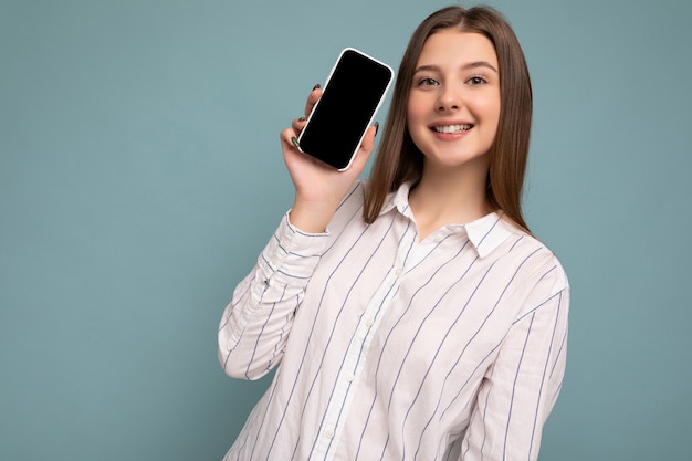 Photo de jeune femme souriante à la recherche de vêtements élégants décontractés debout isolé