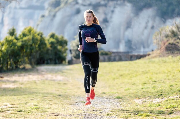 Photo d'une jeune femme sportive qui court sur la montagne dans une nature magnifique.