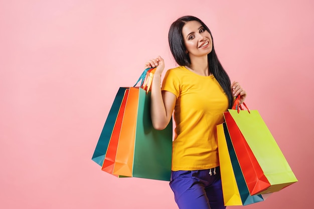 Photo de jeune femme tenir des sacs à provisions vente discount acheter isolé sur fond de couleur rose pastel