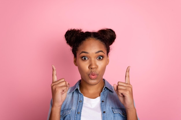 Photo d'une jeune fille africaine faisant la moue des lèvres envoyer un baiser d'air indiquer les doigts espace vide promo isolé sur fond de couleur rose