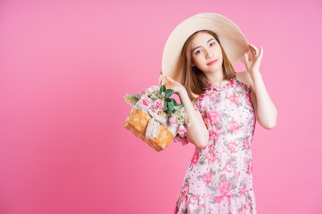 Photo de jeune fille asiatique portant une robe à fleurs sur fond rose