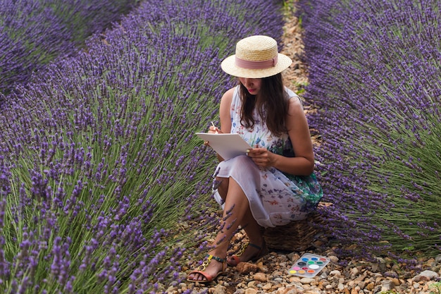 Photo d'une jeune fille dans un champ au milieu des lavandes par temps clair.