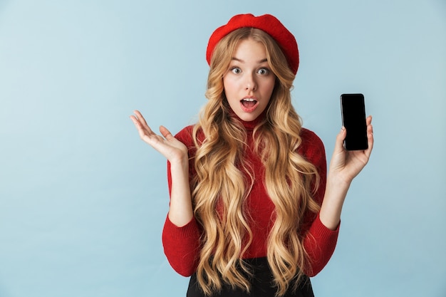 Photo d'une jeune fille élégante de 20 ans portant un béret rouge à l'aide d'un téléphone mobile isolé
