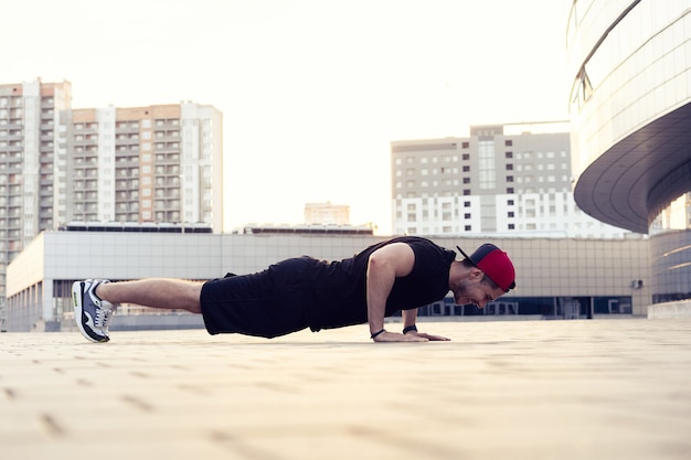 Photo d'un jeune homme athlétique faisant des pompes à l'extérieur. Remise en forme et exercice en milieu urbain à l'extérieur.