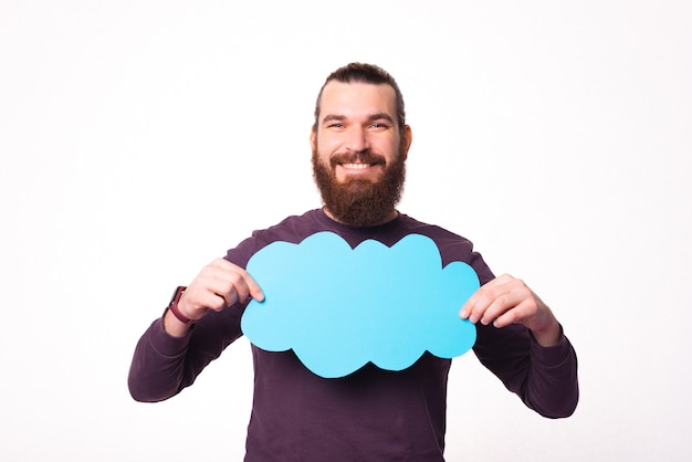 Photo d'un jeune homme barbu joyeux sourit et tient une bulle en forme de nuage