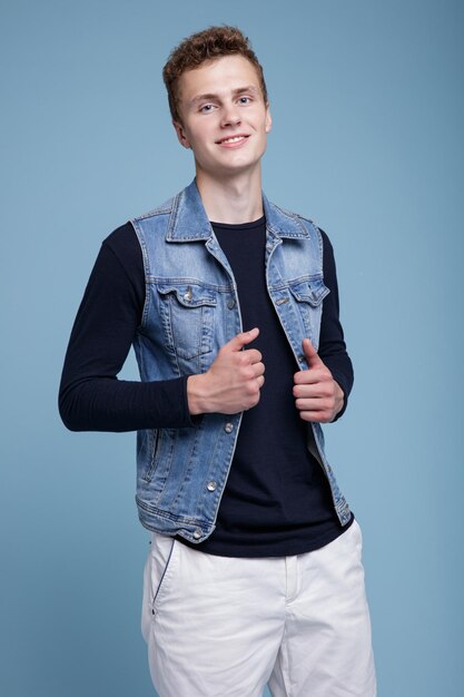 Photo d'un jeune homme avec des boîtes à pizza. Gilet en jean, short blanc, haut noir à manches. Mec posant