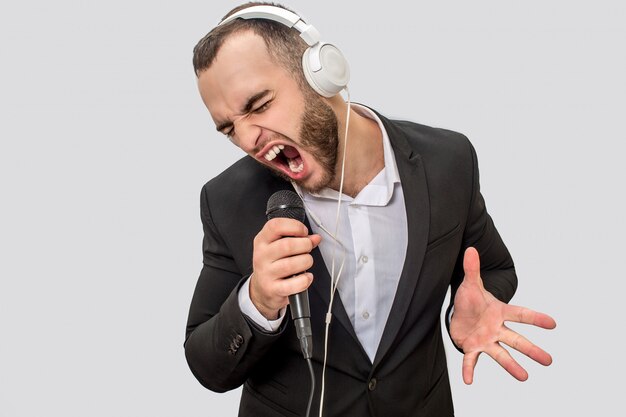 Photo de jeune homme en costume criant dans le microphone. Il chante une chanson. Guy rétrécit et se déplace avec la main.