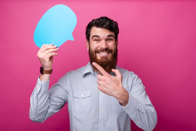 Photo photo de jeune homme en désinvolture pointant sur le discours de la bulle bleue