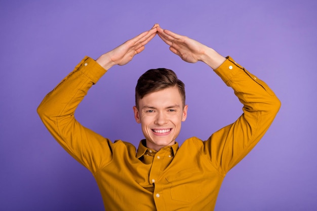 Photo d'un jeune homme excité tenant les bras pour déménager le toit acheter une nouvelle propriété isolée sur fond de couleur violette