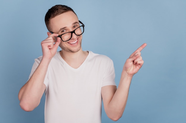 Photo de jeune homme heureux sourire positif pointer du doigt espace vide conseil ad sélectionner suggérer isolé sur fond de couleur bleu