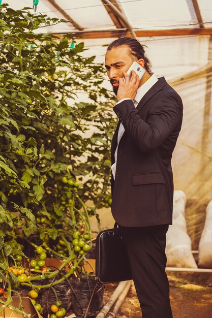 Photo d'un jeune homme parlant au téléphone à la serre