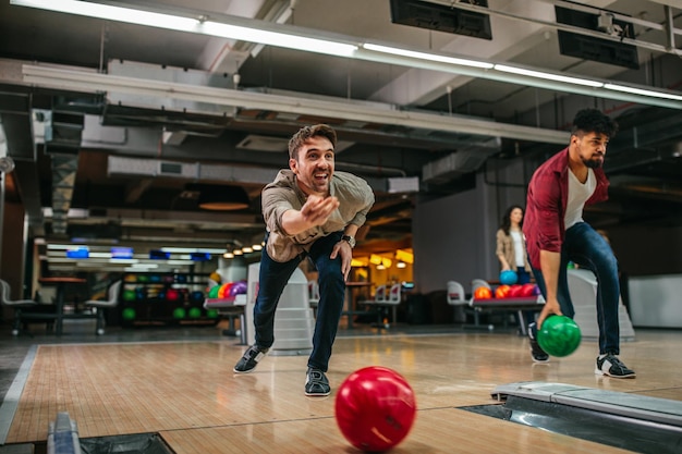 Photo d'un jeune homme séduisant lançant une boule de bowling