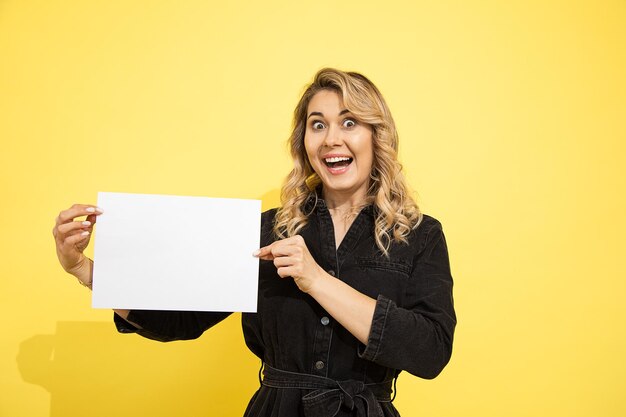 Photo d'une jeune jolie femme blonde rit joyeusement sur fond jaune, prise de vue en studio, garde un blanc vide pour les inscriptions