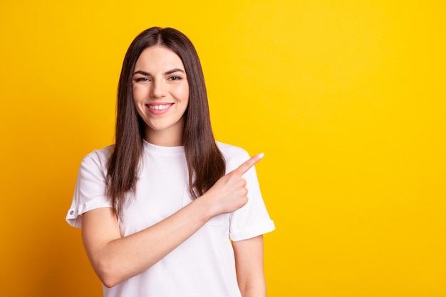 Photo de jeune jolie fille indiquer la promotion de l'espace vide du doigt publicité isolée sur fond de couleur jaune